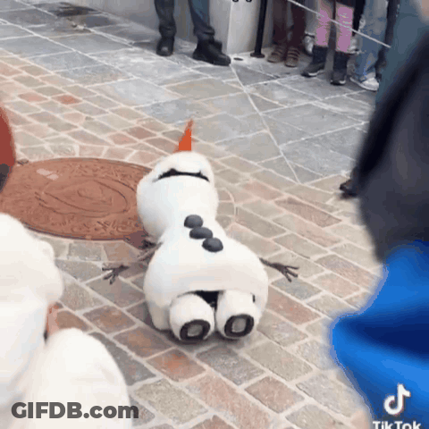 A Stuffed Snowman Is Laying On The Ground With A Manhole Cover In The Background GIF