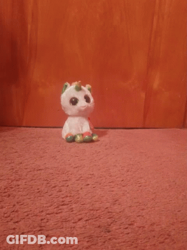A Stuffed Unicorn With A Rainbow Horn Is Looking At The Camera GIF