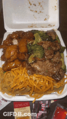 A Styrofoam Container Filled With A Variety Of Food Including Noodles And Broccoli GIF