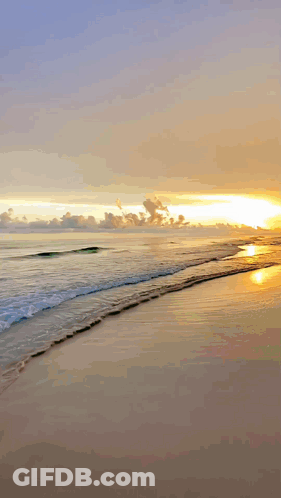 A Sunset Over A Beach With Waves Crashing On The Sand GIF