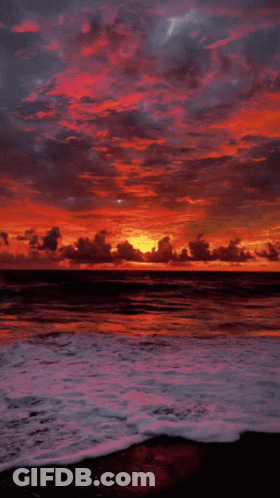 A Sunset Over A Body Of Water With A Few Clouds GIF
