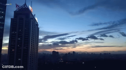 A Sunset Over A City With A Skyscraper In The Foreground That Says ' Jakarta ' On It GIF