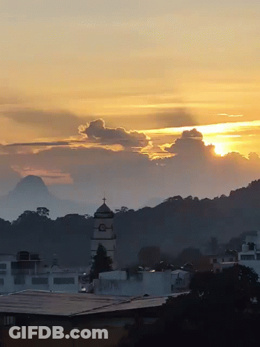 A Sunset Over A City With A Tower In The Foreground GIF