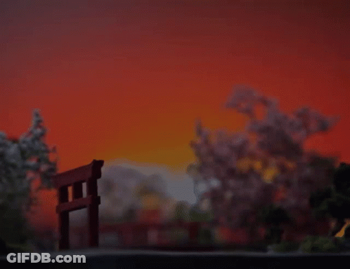 A Sunset With A Torii Gate In The Foreground And Cherry Blossom Trees In The Background GIF