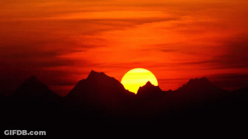 A Sunset With Mountains In The Foreground And A Large Sun In The Background GIF