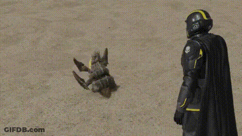 A Superhero In A Black Cape And Helmet Is Standing Next To A Toy Robot . GIF