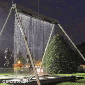 A Swing Set With A Waterfall In The Background GIF