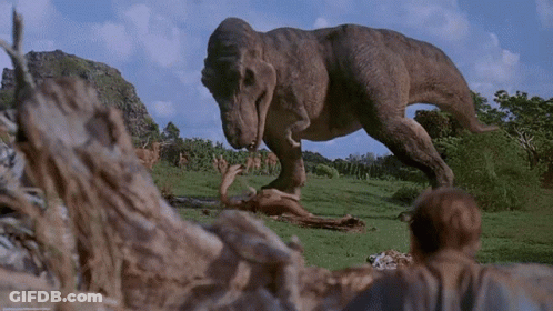 A T-Rex Is Eating A Dead Animal In The Grass GIF