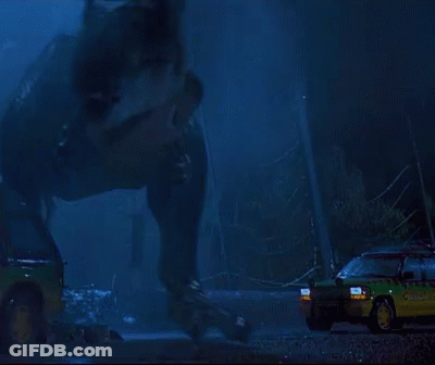 A T-Rex Is Standing In Front Of A Car That Says ' Jurassic Park ' On The Side GIF