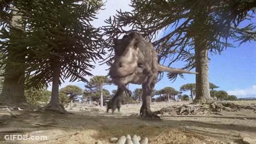 A T-Rex Is Walking Through A Forest With Trees Behind It GIF