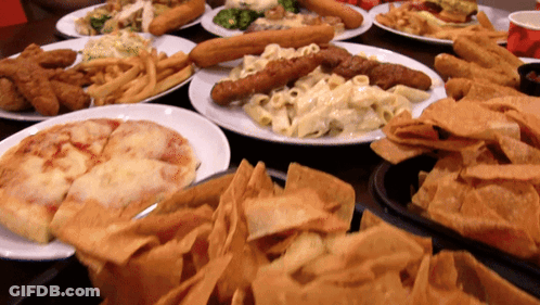 A Table Full Of Plates Of Food Including A Pizza GIF