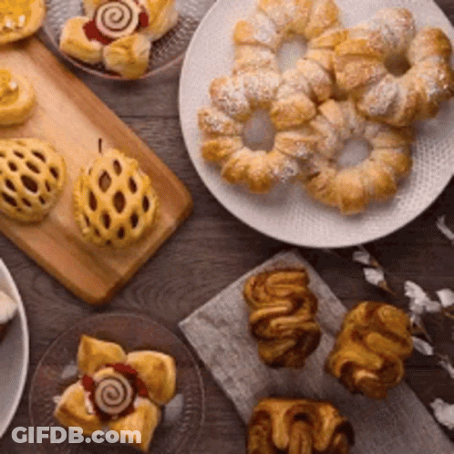 A Table Topped With A Variety Of Pastries And Cakes . GIF