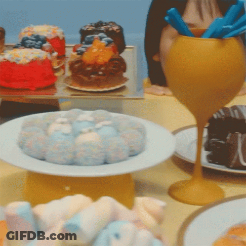 A Table Topped With Plates Of Food Including A Cake GIF