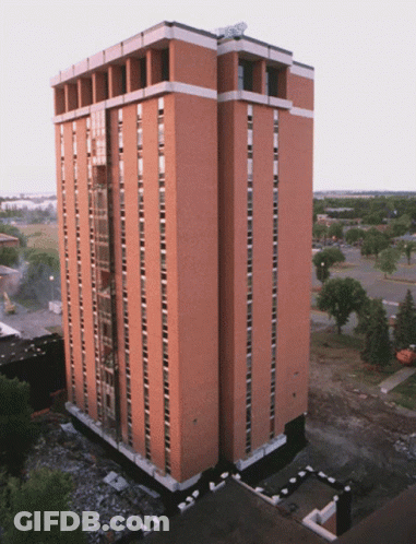 A Tall Brick Building With A Satellite Dish On Top GIF