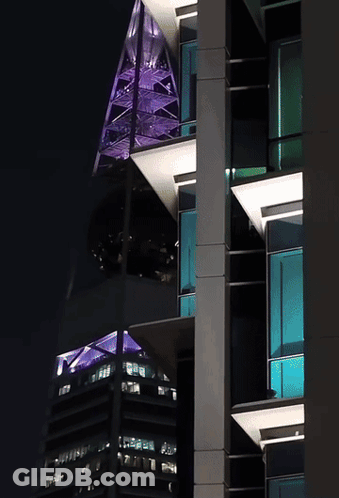 A Tall Building With A Purple Roof And A Green Roof GIF