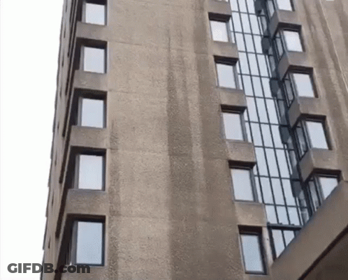 A Tall Building With Lots Of Windows And A White Sky In The Background GIF