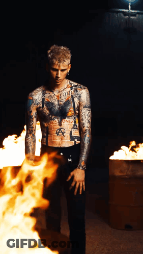 A Tattooed Man Stands In Front Of A Fire That Says Anarchy On His Chest GIF