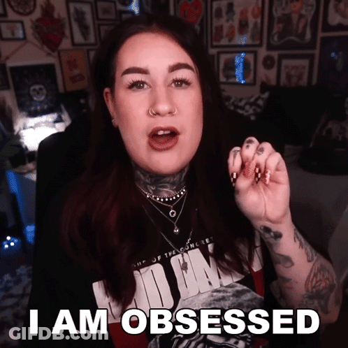 A Tattooed Woman Says I Am Obsessed In Front Of A Wall Of Pictures GIF