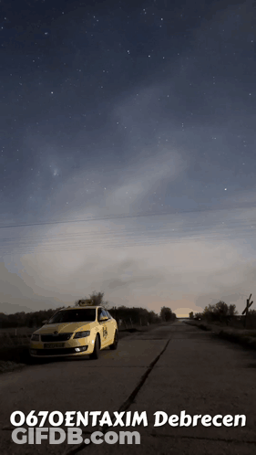 A Taxi Is Parked On The Side Of The Road Under A Starry Sky GIF