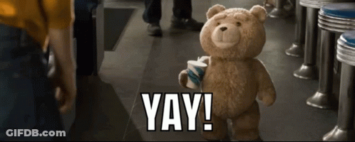 A Teddy Bear In A Diner Holding A Cup That Says Yay GIF