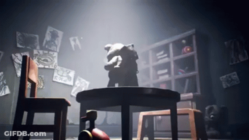 A Teddy Bear Is Sitting At A Table In A Dark Room GIF