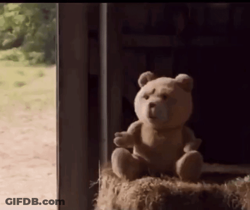 A Teddy Bear Is Sitting On A Bale Of Hay In Front Of A Window . GIF