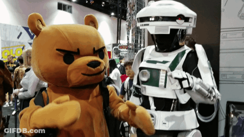 A Teddy Bear Is Standing Next To A Robot Costume GIF
