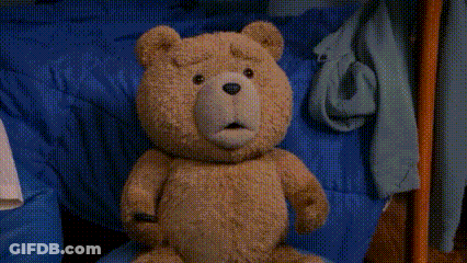 A Teddy Bear Is Standing On A Rug In A Bedroom GIF
