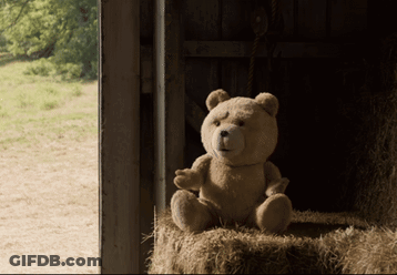 A Teddy Bear Sits In A Pile Of Hay GIF