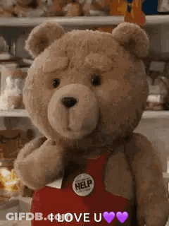 A Teddy Bear Wearing A Red Apron Is Standing In Front Of A Shelf And Says `` I Love You '' . GIF