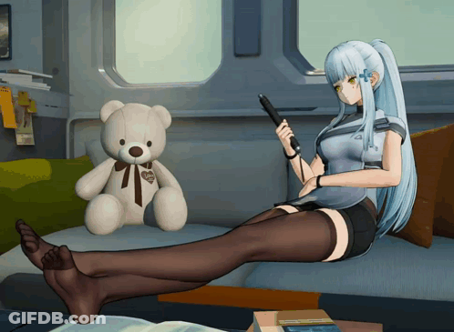 A Teddy Bear With A Heart On It Sits Next To A Girl Laying On A Couch GIF