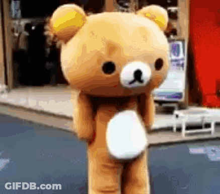 A Teddy Bear With A Yellow Ear Is Standing On A Street GIF