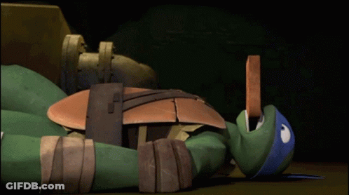A Teenage Mutant Ninja Turtle Is Laying On The Floor GIF