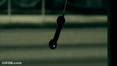A Telephone Is Hanging From A Pole In The Dark . GIF