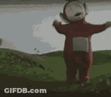 A Teletubbies Character Is Standing In A Grassy Field . GIF