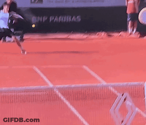 A Tennis Ball Is Being Thrown In The Air On A Red Court GIF