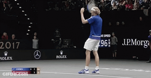 A Tennis Player Holds Up His Racket In Front Of A Sign That Says Rolex GIF