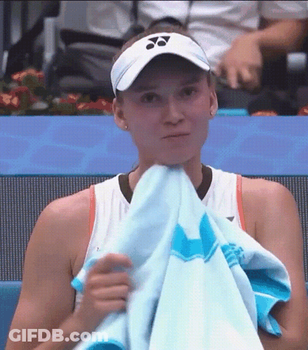 A Tennis Player Is Covering Her Face With A Towel While Wearing A Visor . GIF