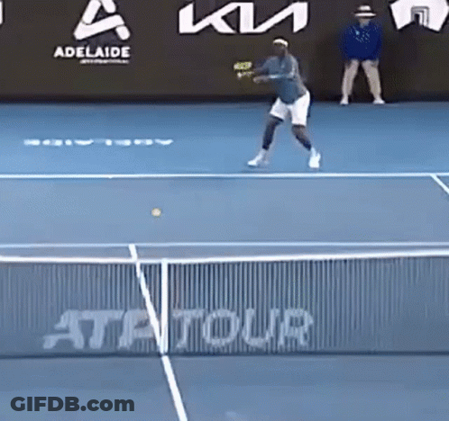 A Tennis Player Is Hitting A Tennis Ball On A Blue Court GIF