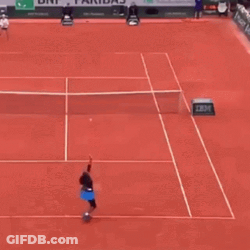 A Tennis Player Is Hitting A Tennis Ball On A Red Tennis Court . GIF