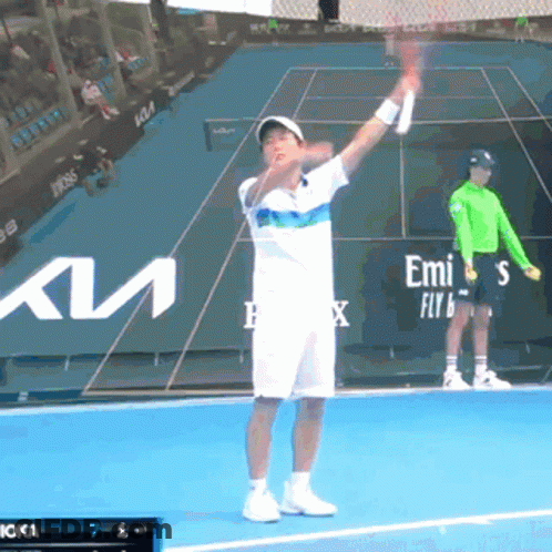 A Tennis Player Is Holding A Racquet On A Court With Emirates In The Background GIF