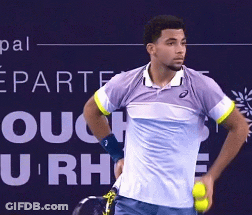 A Tennis Player Is Holding A Tennis Ball In Front Of A Sign That Says U Rh GIF