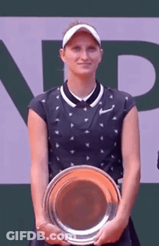 A Tennis Player Is Holding A Trophy And Smiling . GIF