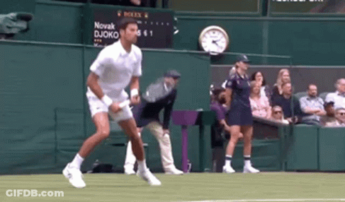 A Tennis Player Is Jumping In The Air On A Tennis Court GIF