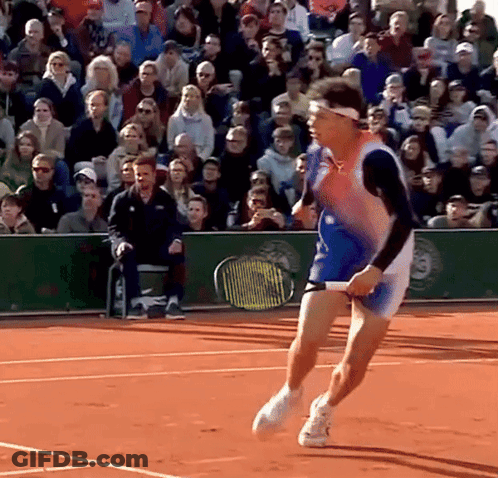 A Tennis Player Is Running On A Court With A Crowd Behind Him GIF