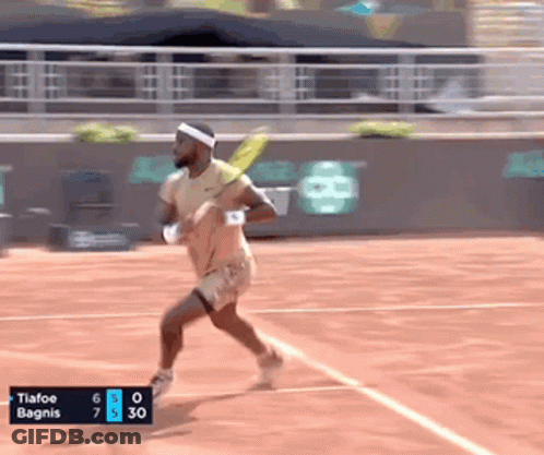 A Tennis Player Is Running On A Court With A Scoreboard That Says Tiafoe Bagnis At The Bottom GIF