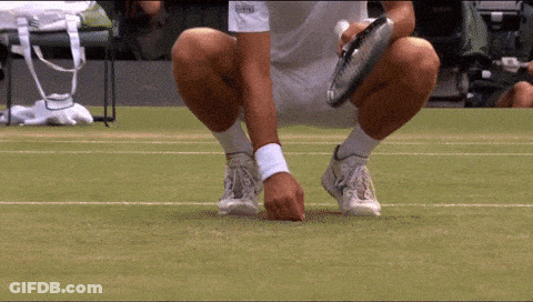 A Tennis Player Is Squatting Down On The Court With A Racket In His Hand GIF