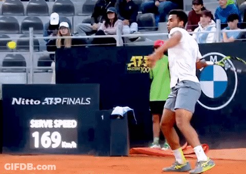 A Tennis Player Is Swinging A Racket In Front Of A Sign That Says Nitto Atp Finals GIF