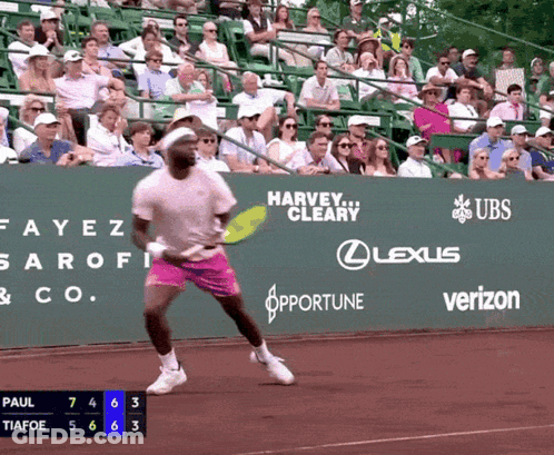 A Tennis Player Is Swinging A Tennis Racquet In Front Of A Green Wall That Says Harvey Cleary On It GIF