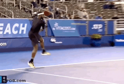A Tennis Player Jumps In The Air While Playing Tennis GIF